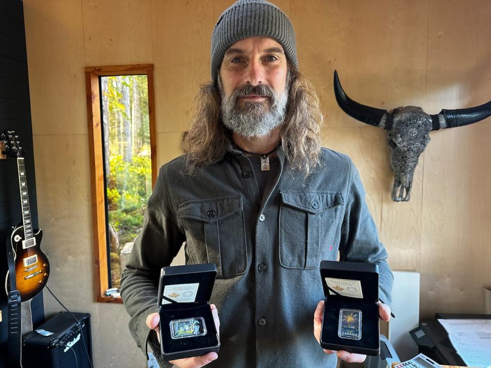 Graphic designer Patrick Bélanger with the two coins he has designed for the Royal Canadian Mint. His newest, released in 2023, is the Duncan Incident (left). He also designed a coin in 2021(right) depicting the Montréal Incident, which shows a mysterious object floating above the city's Hôtel Bonaventure on the night of Nov. 7, 1990. 