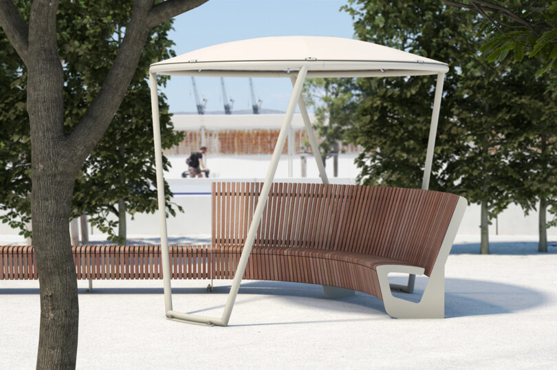 A curved wooden bench with a white canopy in a public space.