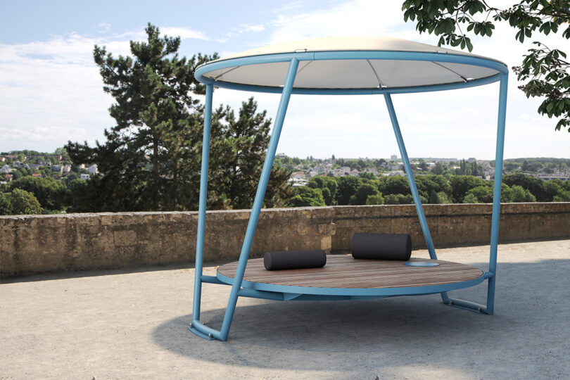 A round platform bench with a blue canopy in a public space.