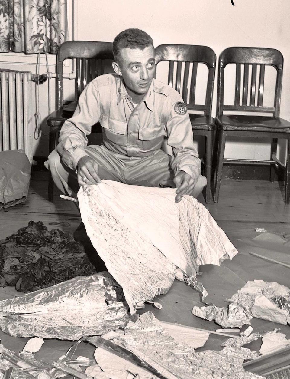 Major Jesse A. Marcel (looking right) of Houma, Louisiana, holding foil debris from Roswell, New Mexico UFO crash site, July 1947.
